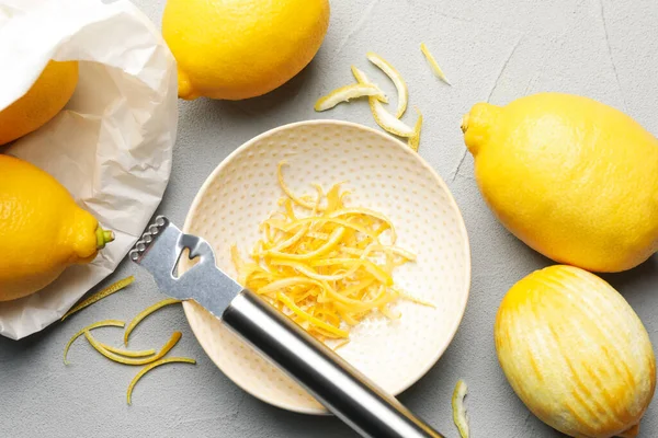 Taze limonlar, keyifli ve zester aletli gri masada, düz yerde.