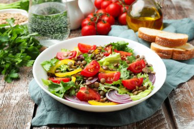 Lezzetli mercimek salatası ve malzemeler ahşap masada, yakın plan.