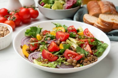 Beyaz masada sunulan mercimek ve sebzeli leziz salata.