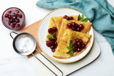 Beyaz mermer masada servis edilen kiraz reçelli leziz krepler.