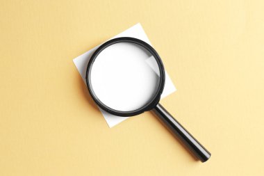 Büyüteç ve bej arkaplan üzerine boş not, üst görünüm