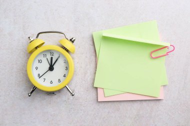 Kağıt ataç ve alarm saati ile boş notlar gri desenli tablo, düz yatıyordu