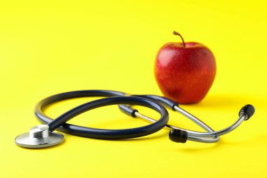Sarı arka planda olgun elma ve steteskop, seçici odaklanma. Metin için boşluk