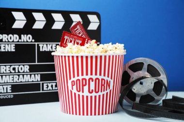 Kağıt bardakta lezzetli patlamış mısır, sinema biletleri, makara ve alkışlar mavi arka planda, yakın plan