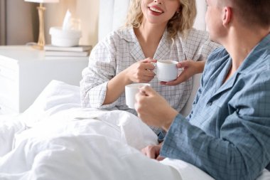 Evdeki sıcak içeceklerin tadını çıkaran sevimli çift, yakın plan.