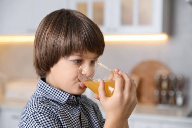Çocuk evde taze portakal suyu içiyor.