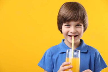 Sarı arka planda bir bardak taze portakal suyu olan çocuk. Metin için boşluk