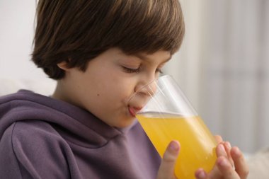 Çocuk evde taze portakal suyu içiyor.