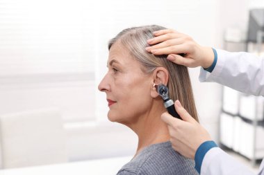 Duyma testi. Klinikte otoskopla hastanın kulağını muayene eden doktor, yakın plan. Metin için boşluk