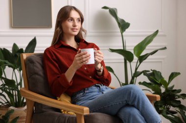 Evdeki koltukta bir fincan aromatik kahvesi olan kadın. Metin için boşluk