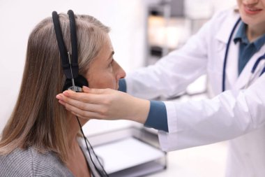 Duyma testi. Doktor klinikte hastanın işitsel kulaklıklarını ayarlıyor.