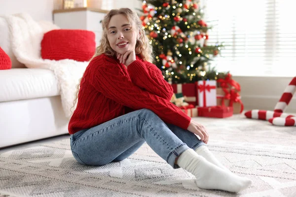 Evdeki bulanık ışıklara karşı süveterli, gülümseyen kadın. Mutlu Noeller ve mutlu yıllar.