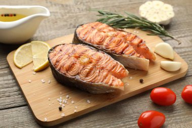 Ahşap masada servis edilen lezzetli ızgara somon biftekleri, yakın plan.