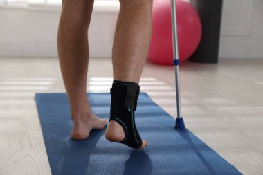 Dirsek değneğini içeride kullanan yaralı bir adam, yakın plan.