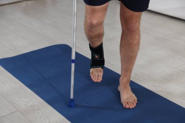 Dirsek değneğini içeride kullanan yaralı bir adam, yakın plan.