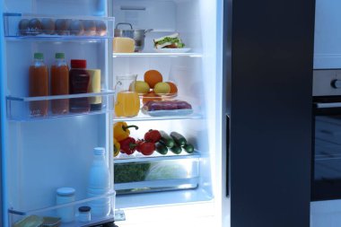 Mutfakta farklı taze gıda ürünleri olan modern buzdolabı.