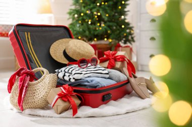 Giysilerin, hediyelerin ve diğer eşyaların olduğu bavul festival süslemeli odada. Noel tatili