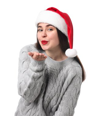 Noel Baba şapkalı güzel kadın beyaz arka planda hava öpücüğü veriyor. Noel sezonu