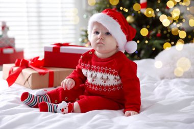 Noel Baba şapkalı şirin bir bebek ve evde yatağında hediye kutuları. Noel sezonu