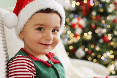 Noel Baba şapkalı küçük çocuk Noel için dekore edilmiş odasındaki koltukta, mesaj için de yeri var.