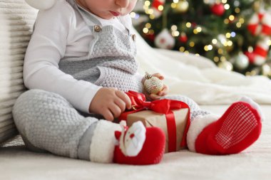 Noel için dekore edilmiş koltukta hediyeli küçük çocuk, yakın plan.