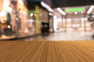 Boş ahşap masa, bulanık alışveriş merkezi manzarasına karşı. Tasarım için boşluk