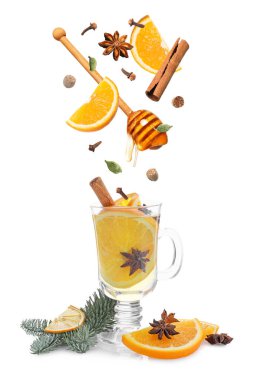 Sıcak şarap tarifi. Baharatlar ve diğer malzemeler cam bardağa dökülüyor ve beyaz arka planda içecek var.