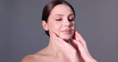 Doktor, gri arka planda estetik ameliyattan önce hastanın yüzünü kontrol ediyor.