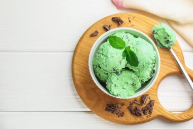 Çikolata parçalı lezzetli dondurma ve beyaz ahşap masada kaşık, üst manzara. Metin için boşluk