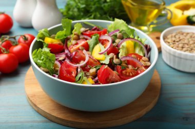 Lezzetli mercimek salatası ve malzemeler açık mavi ahşap masada, yakın plan.