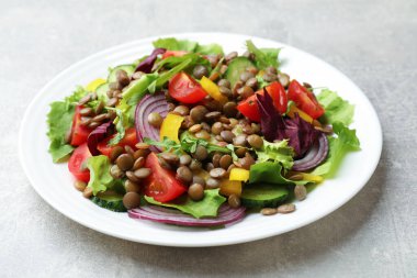 Gri masada mercimek ve sebzeli lezzetli salata, yakın plan.