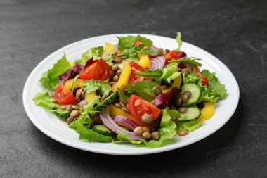 Gri desenli masada mercimek ve sebzeli lezzetli salata, yakın plan.