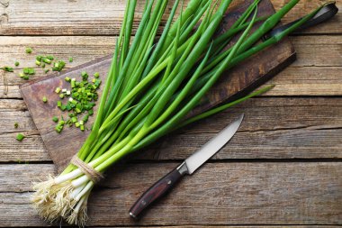 Taze taze soğan ve bıçak ahşap masada, üst tarafta.