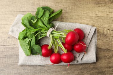 Yeşil yapraklı taze turplar ve ahşap masa üzerinde peçete.