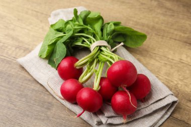 Yeşil yapraklı taze turplar ve ahşap masa peçetesi, yakın plan.