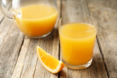 Taze portakal suyu ve meyve dilimi ahşap masada, yakın plan.