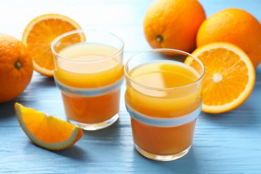 Taze portakal suyu ve açık mavi ahşap masada meyveler, yakın plan.