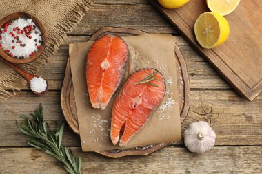 Taze somon fileto, tuz, sarımsak, biberiye ve limon parçaları ahşap masada, düz yatıyordu.