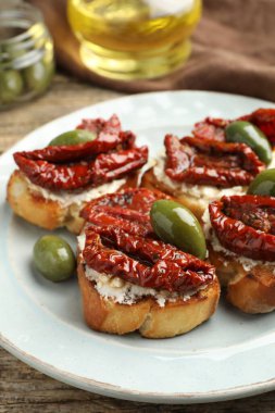 Krem peynirli lezzetli bruschettalar, güneşte kurutulmuş domatesler ve yeşil zeytinler masada, yakın plan.