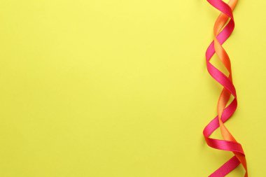 Sarı arka planda parlak pembe ve turuncu kurdele, üst manzara. Metin için boşluk