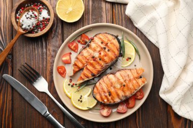 Lezzetli ızgara somon bifteği limon, biberiye ve domatesle servis edilir.