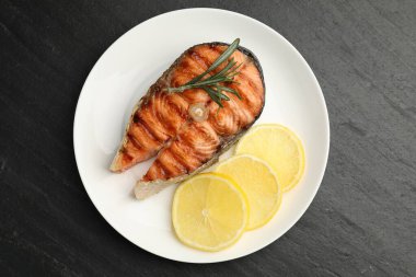 Biberiye ve limonla servis edilen ızgara somon bifteği.