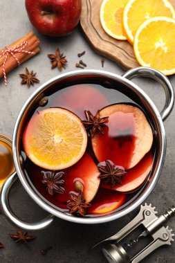 Lezzetli sıcak şarap, malzemeler ve tirbuşon gri desenli masada, düz yerde.