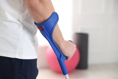 Evde dirsek değneği olan bir adam var, yakın plan. Metin için boşluk