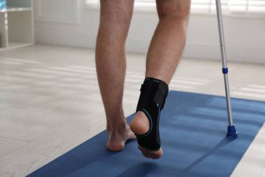 Dirsek değneğini içeride kullanan yaralı bir adam, yakın plan.