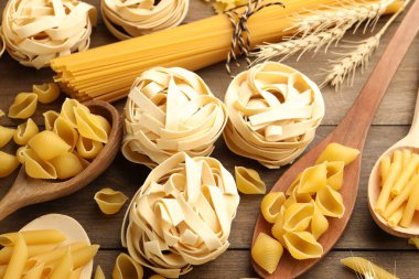 Farklı türde çiğ makarna ve çiviler tahta masanın üstünde.