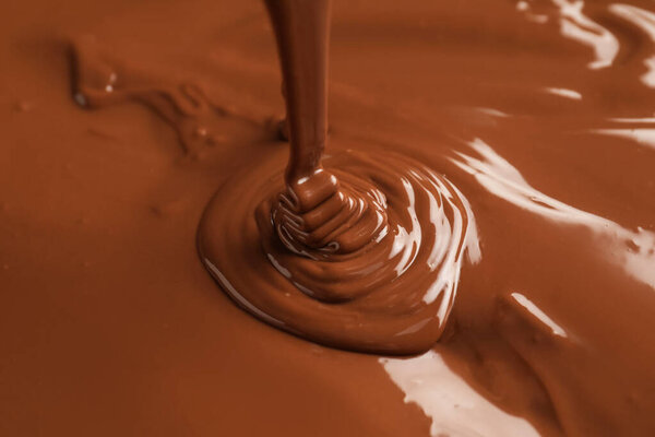 Tasty melted chocolate flowing down, closeup view