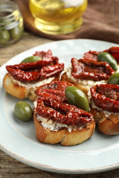 Krem peynirli lezzetli bruschettalar, güneşte kurutulmuş domatesler ve yeşil zeytinler masada, yakın plan.