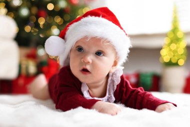 Noel Baba şapkalı şirin bebek Noel ışıklarına karşı yumuşak battaniyeli, bokeh etkisi