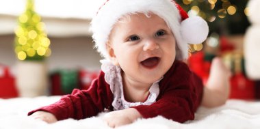 Noel Baba şapkalı, yumuşak battaniyeli şirin bir bebek Noel ışıklarına karşı, mesaj için yer. Bokeh etkisi